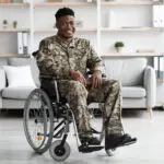 smiling african american veteran in camouflage uniform sitting in a wheelchair. disability tracking and hiring.