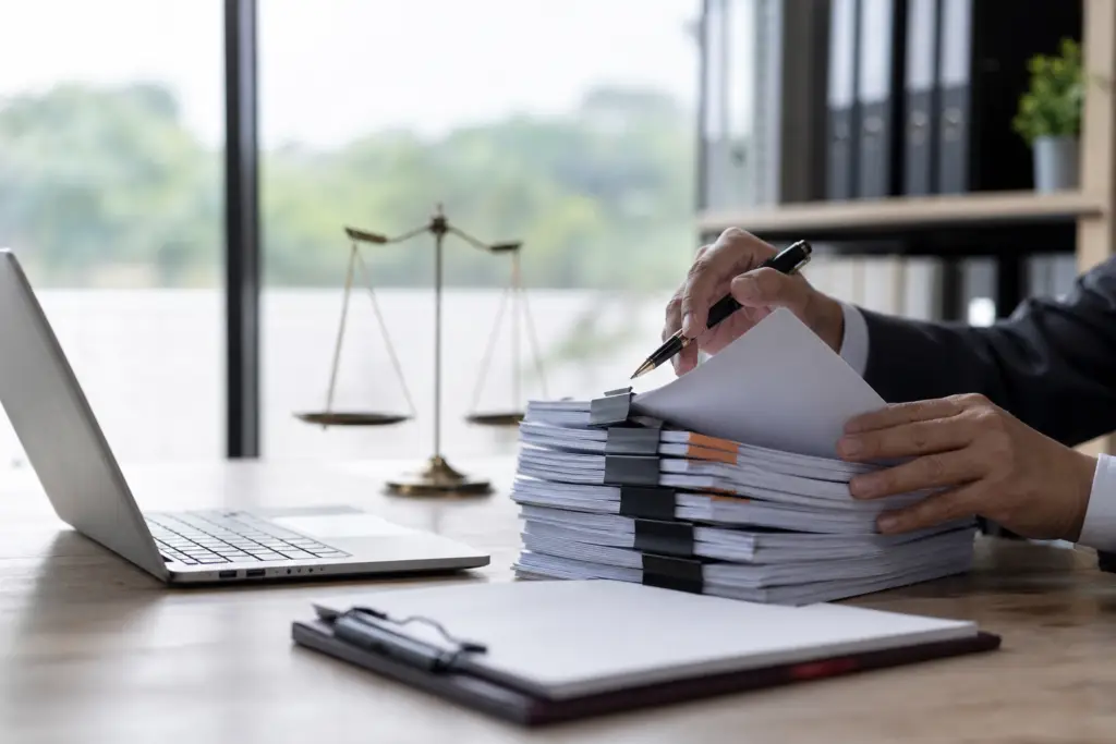 attorney reviewing documents, laptop, and scales of justice for ofccp audit preparation.